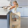 bambina su torre montessori in cucina mentre partecipa alle attività quotidiane